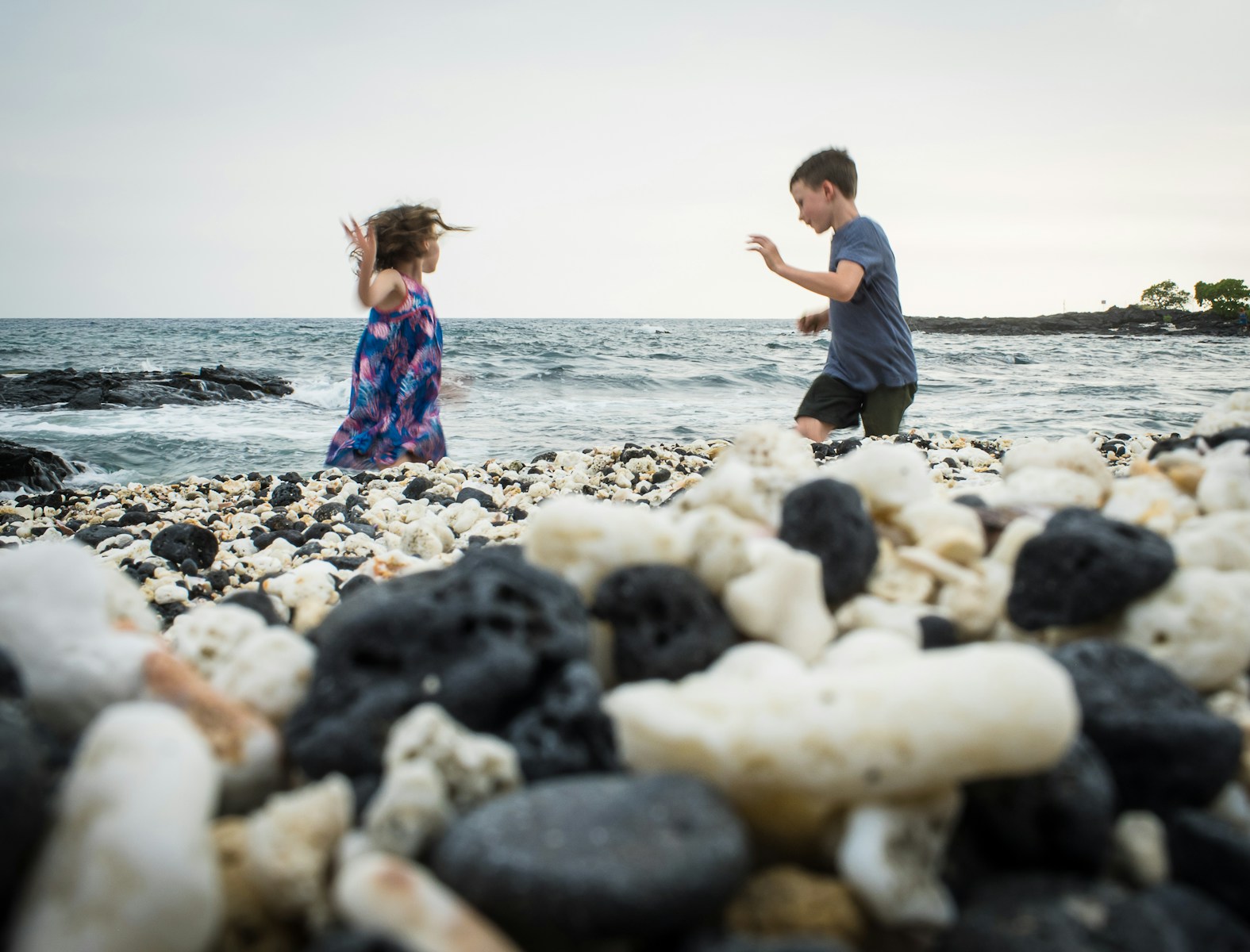 girl in blue and white dress standing on rocky shore during daytime