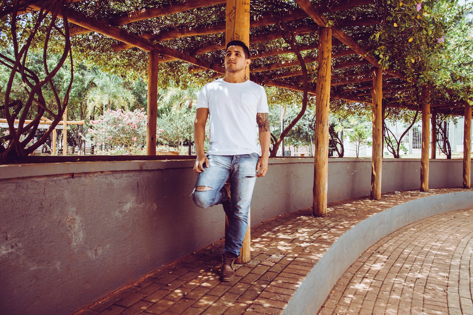 a man leaning against a wall with his hand in his pocket