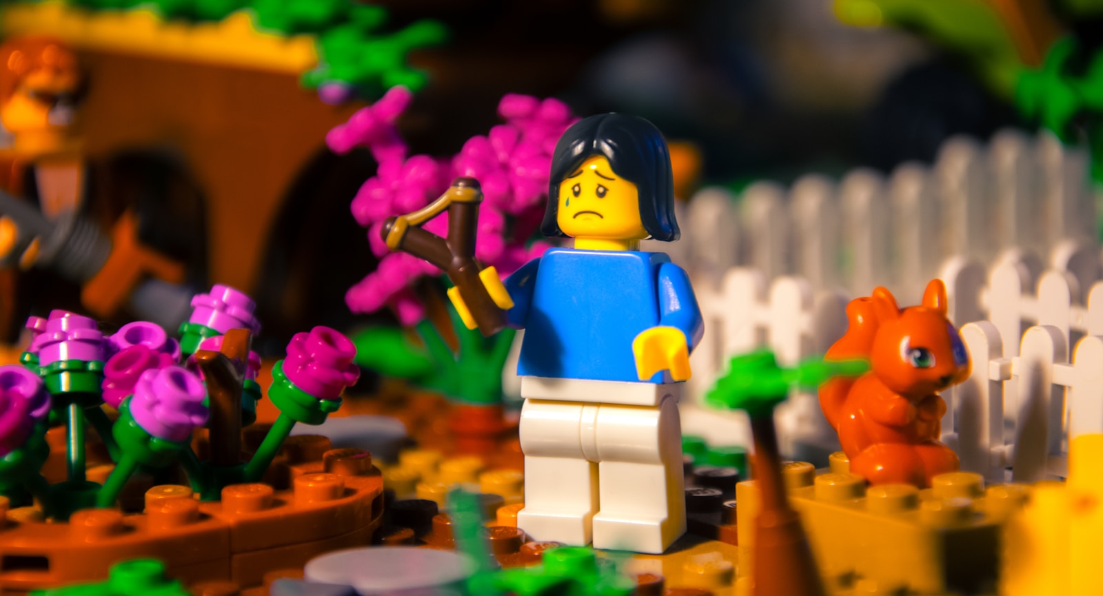 a lego figure standing in front of a flower garden