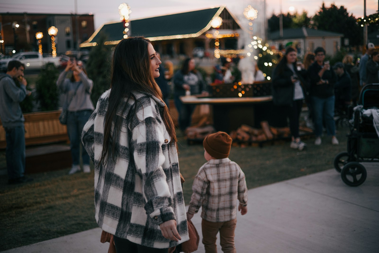 a woman holding a child's hand as they walk down a sidewalk