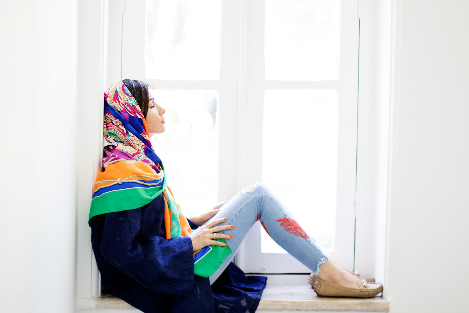 woman in blue and yellow long sleeve shirt and blue denim jeans sitting on white table