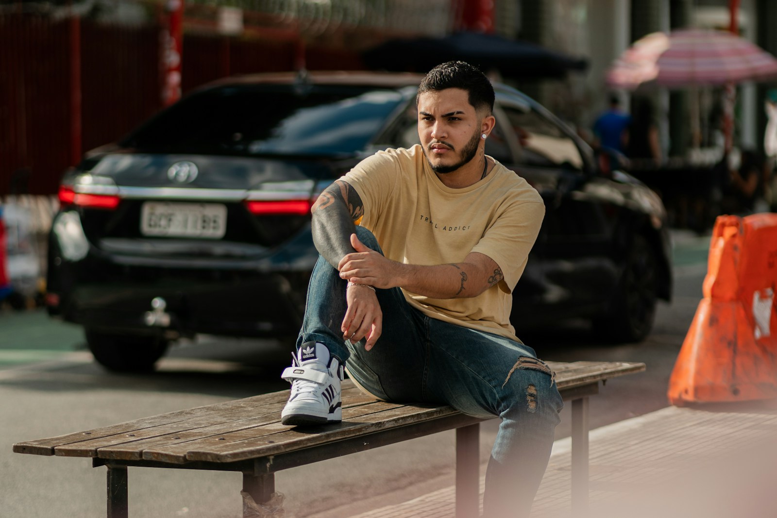 a man sitting on a bench in front of a car