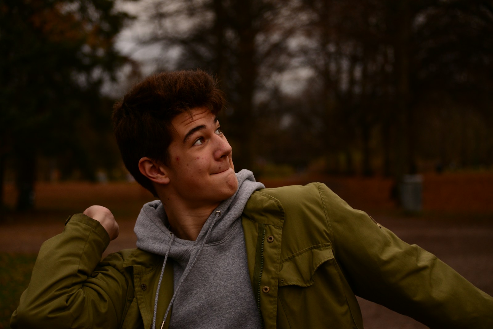 man in green jacket standing near trees during daytime