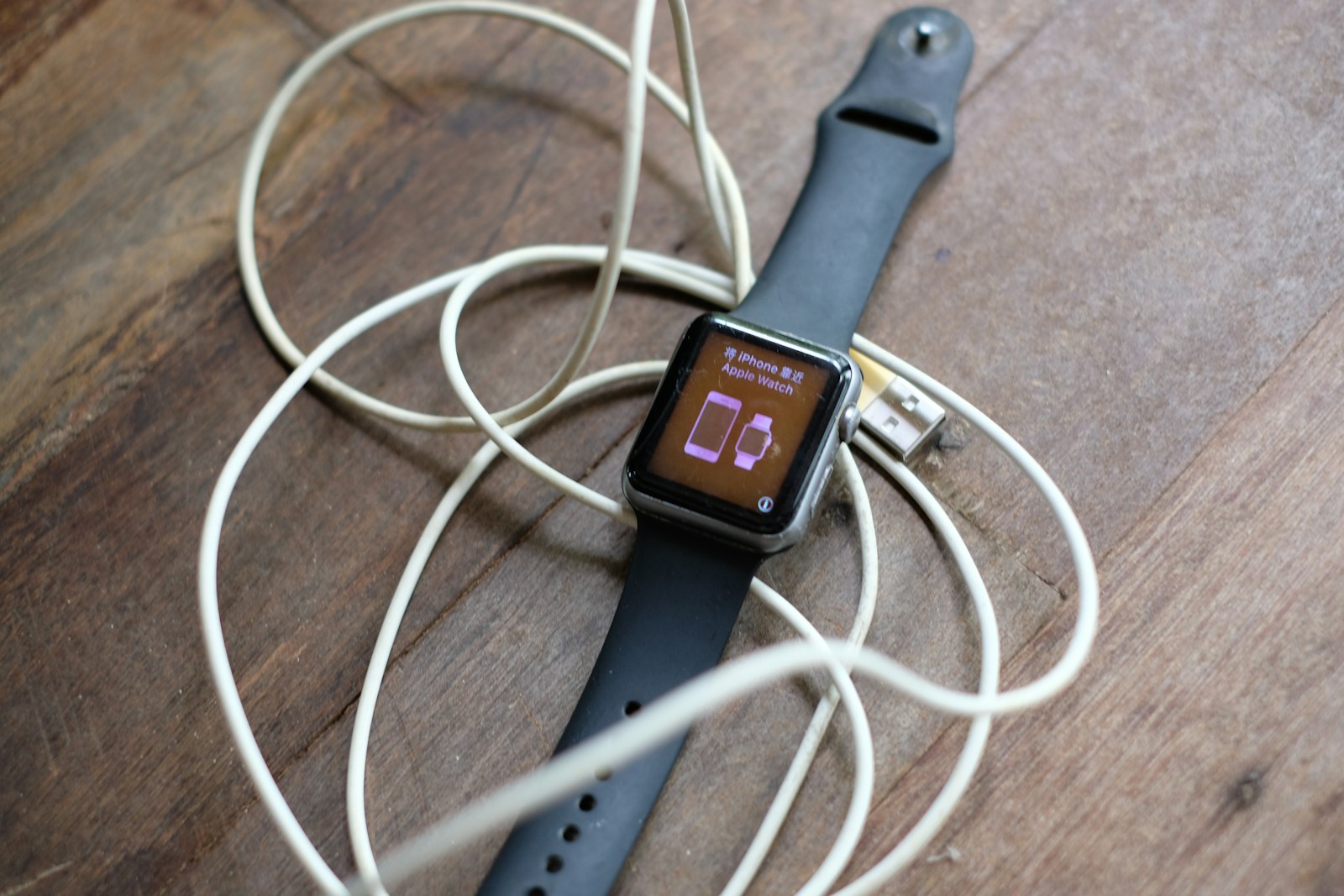 a smart watch connected to a charger on a wooden table