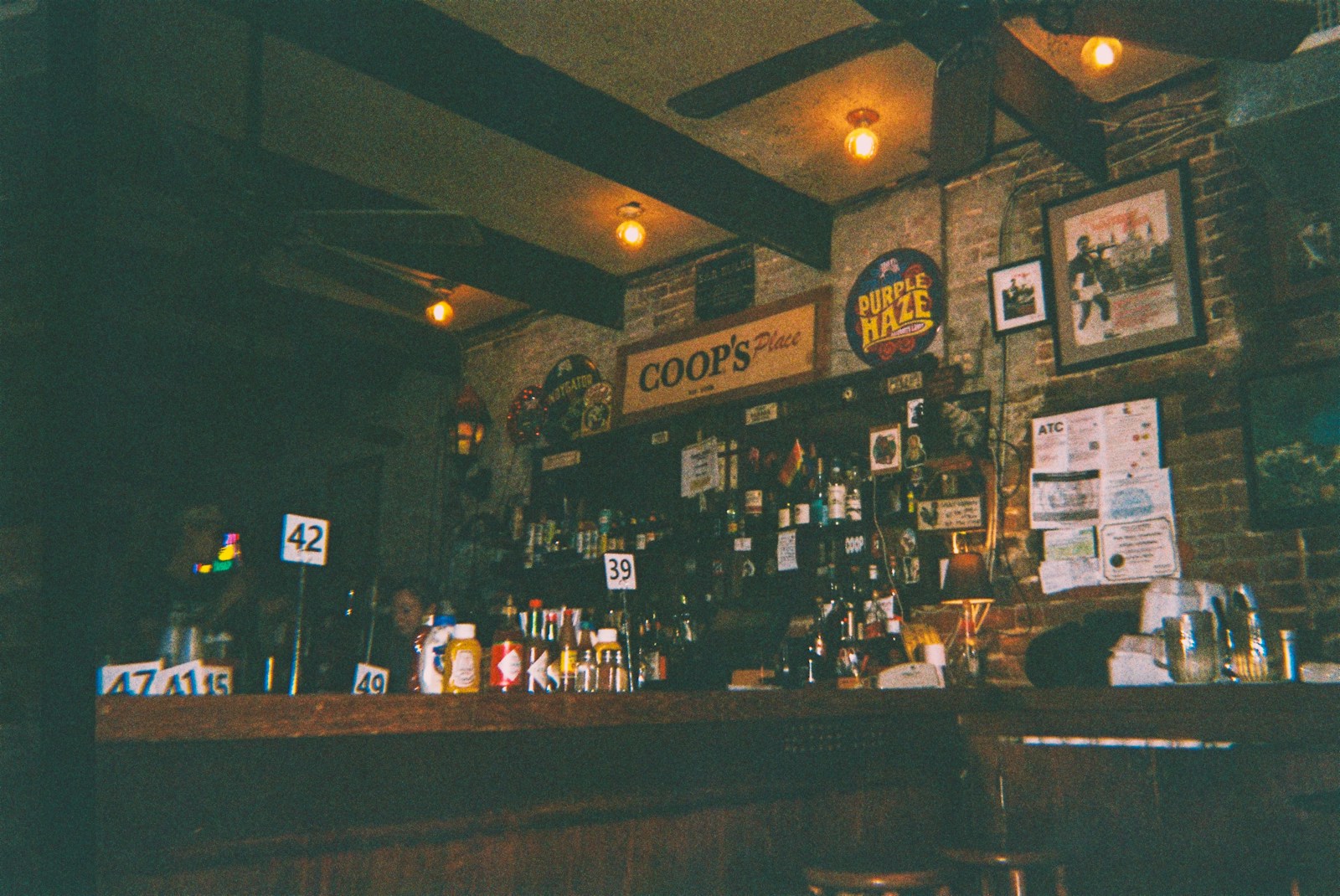 A dimly lit bar interior with bottles and signs.