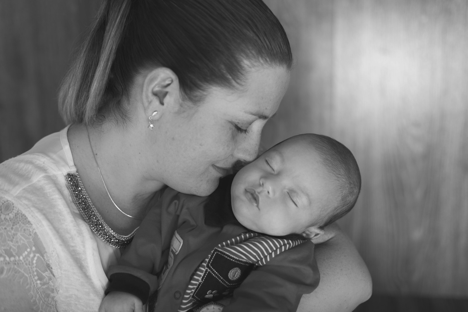 woman kissing baby in grayscale photography