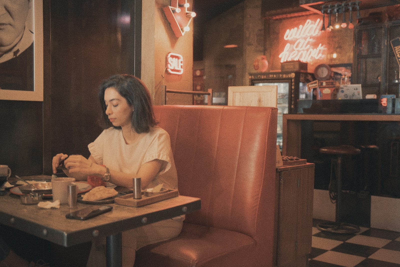 A young woman eating in a retro diner booth.