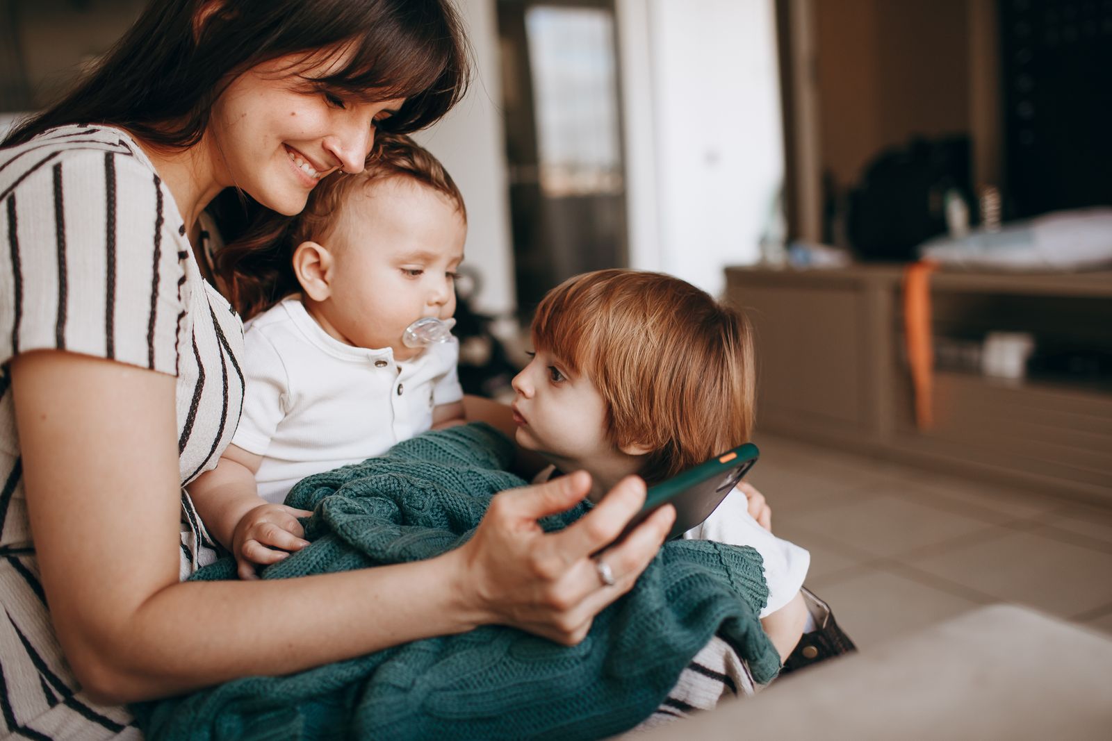 Mother with two children sharing a heartfelt moment indoors, exuding warmth and togetherness.