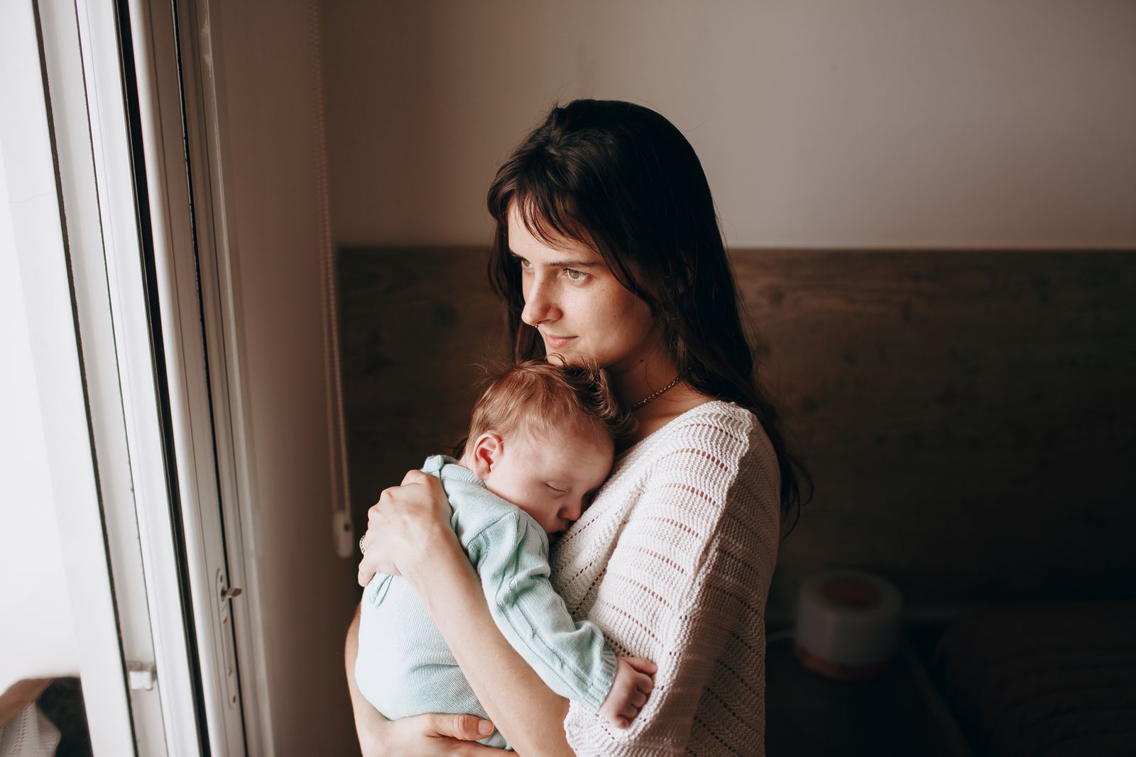 A serene image of a mother lovingly holding her sleeping baby indoors.