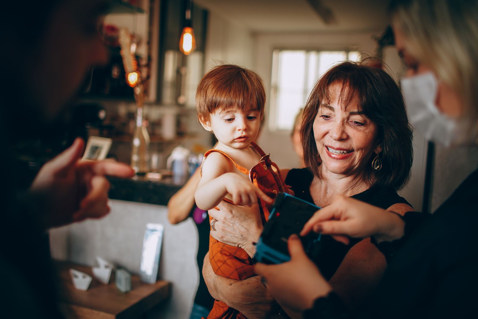 Heartwarming moment of a grandmother holding a child at a family gathering indoors.
