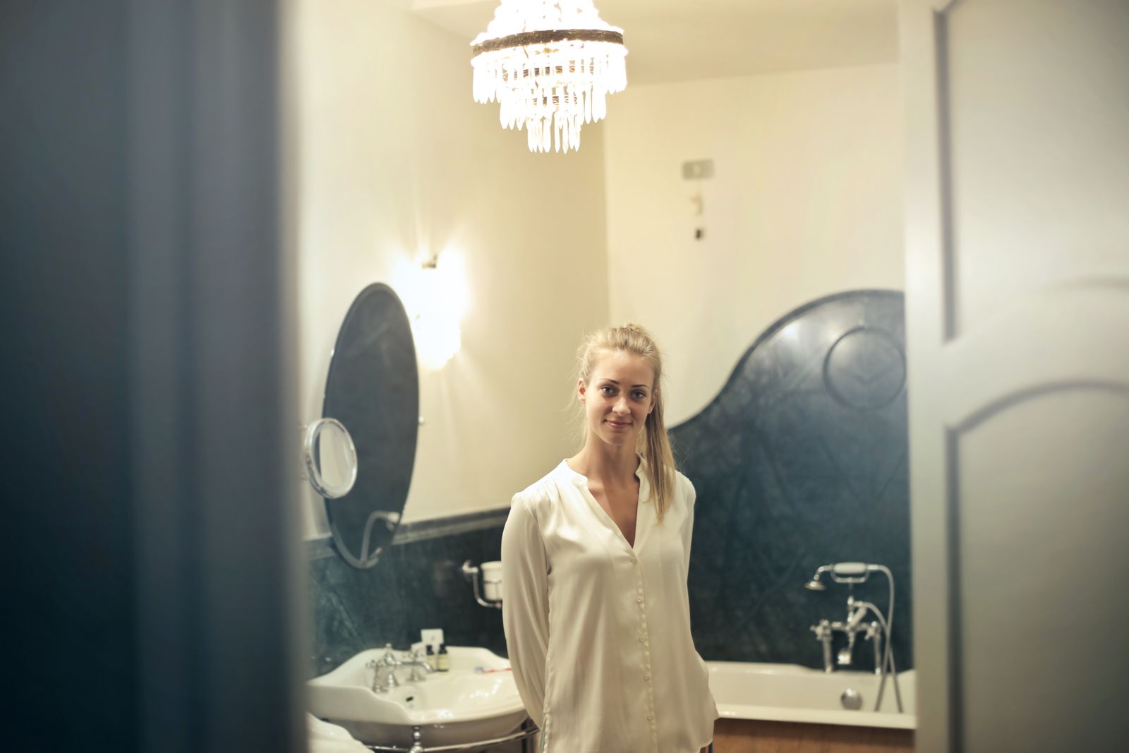 Portrait of a smiling woman in a stylish bathroom setting, showcasing luxurious decor and ambient lighting.