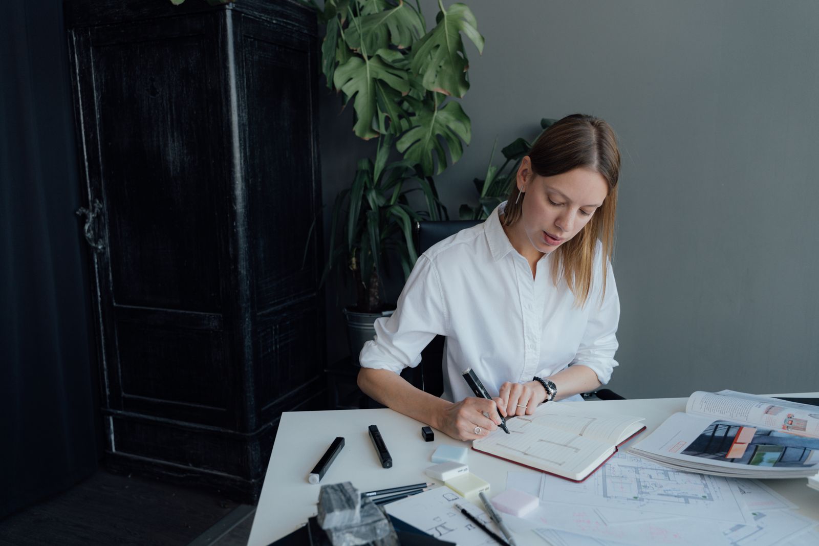 A young female architect working on floor plans at home, blending creativity and professionalism.