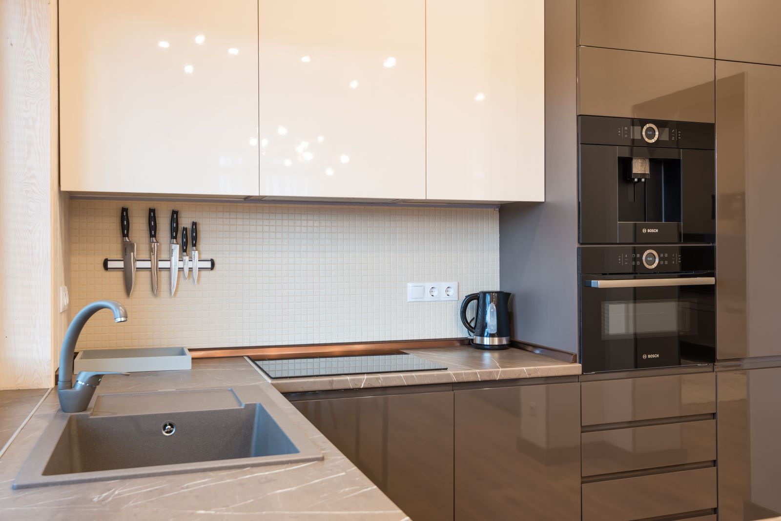 Interior of kitchen with minimalist glossy furniture and modern appliances in light contemporary apartment