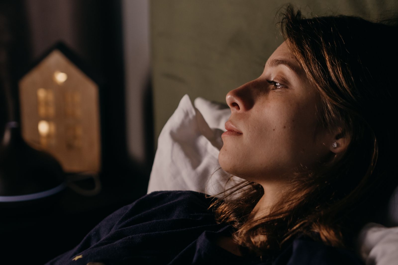 Close-up of a woman resting indoors at night, showcasing a serene and relaxed atmosphere.
