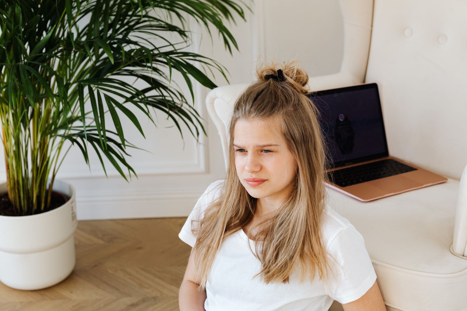A teenage girl sits by a laptop and plant, exuding a calm and modern vibe.