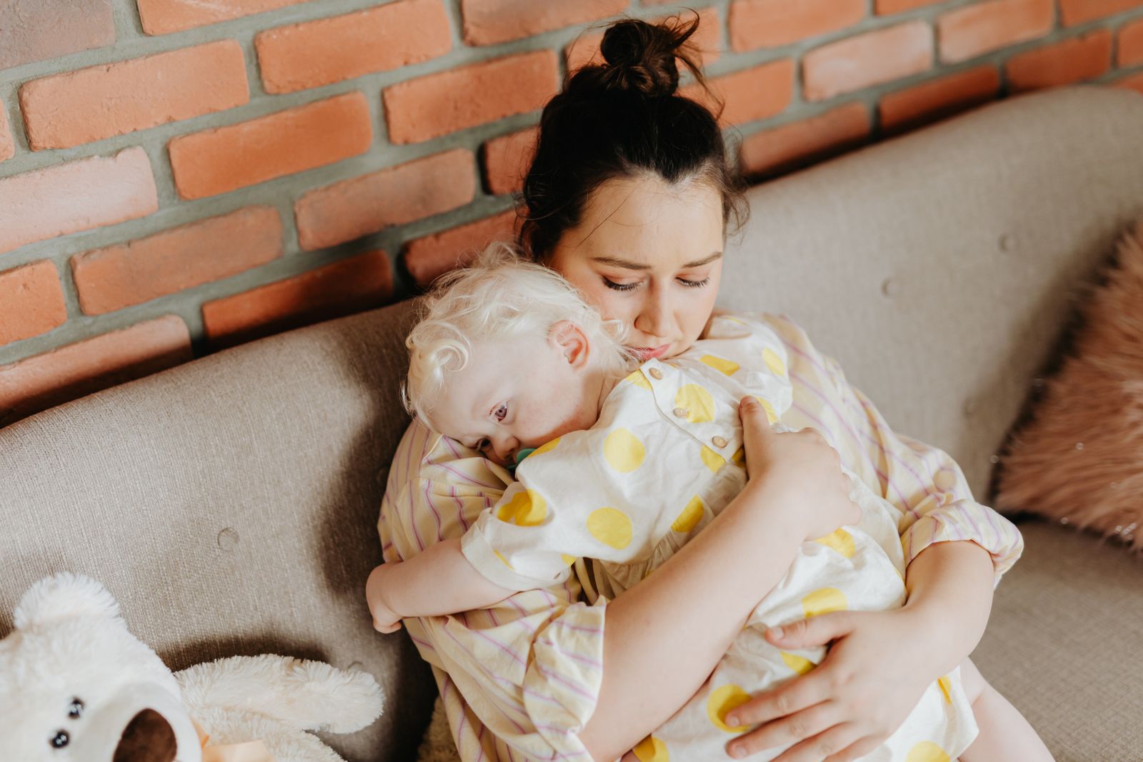 A mother embracing her child lovingly on a sofa, conveying warmth and affection.