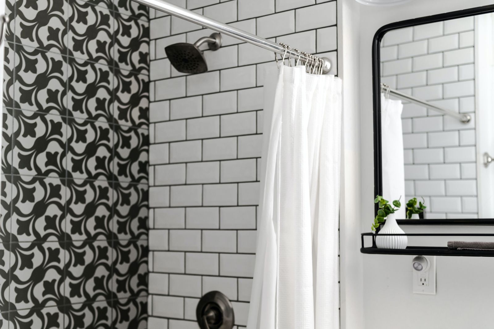 Contemporary bathroom featuring patterned and subway tiles with a minimalist mirror and white shower curtain.