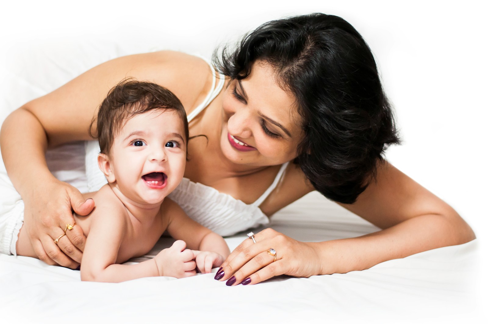 Loving mother smiles at her adorable, laughing baby.