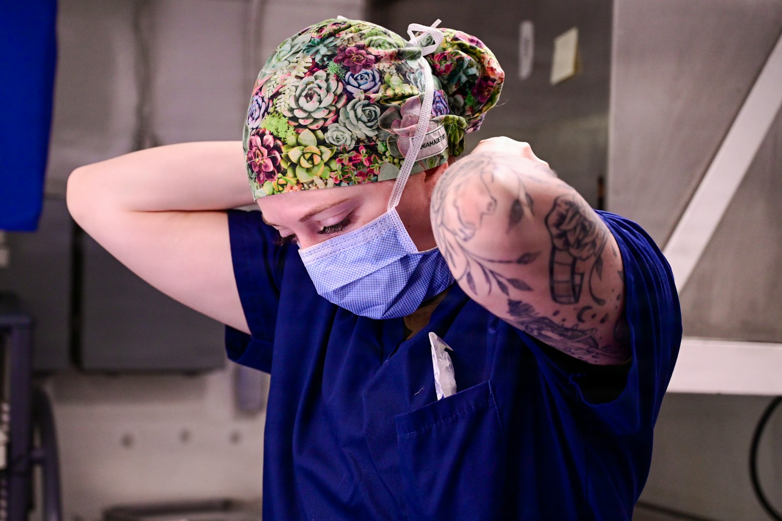 Healthcare professional adjusting a blue surgical mask.