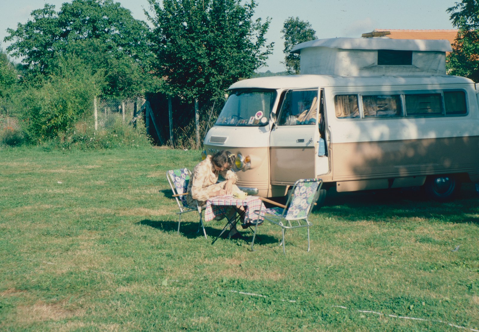 a couple of people sitting in chairs outside by a van