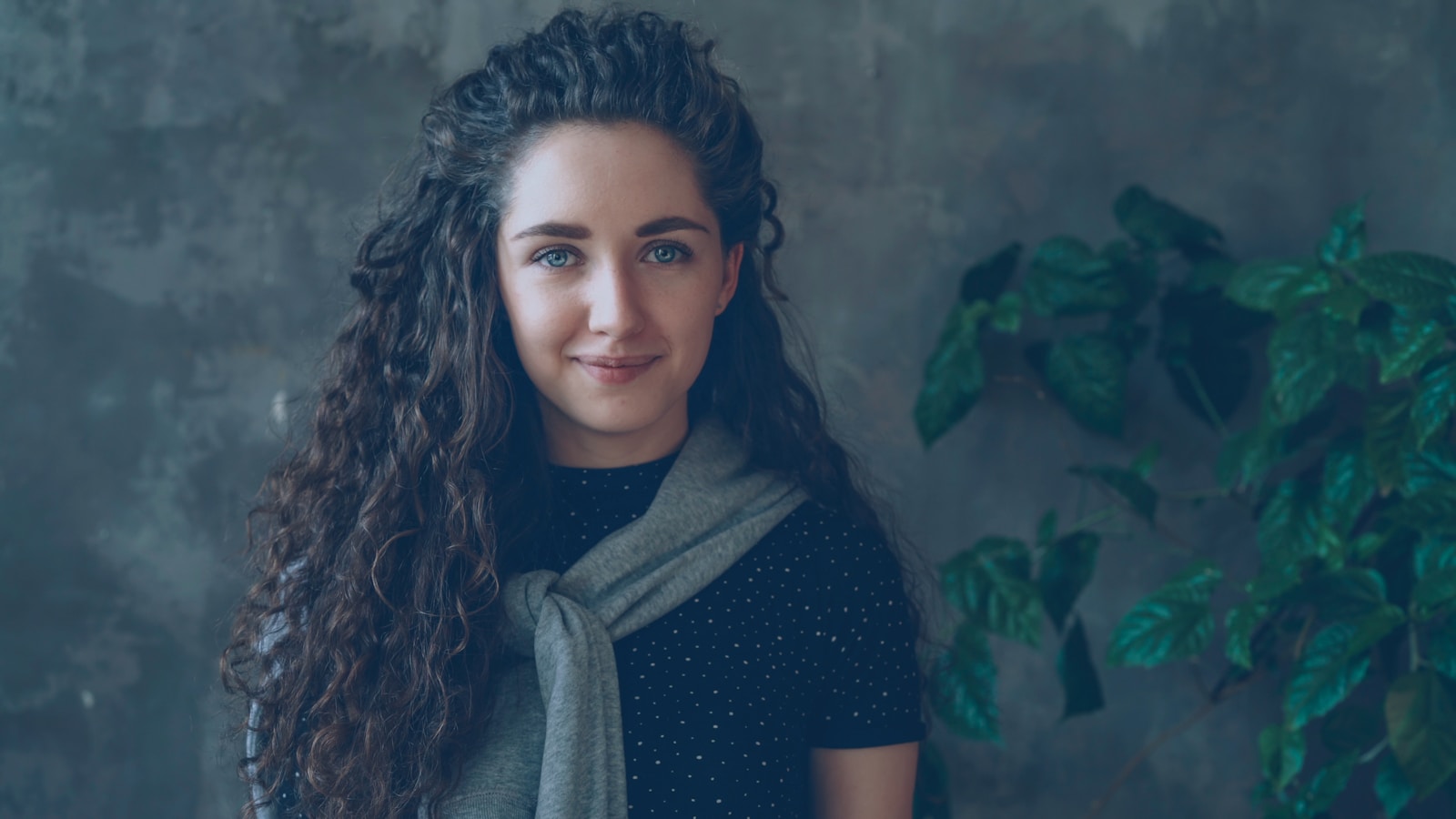 A woman with curly hair smiles at the camera.