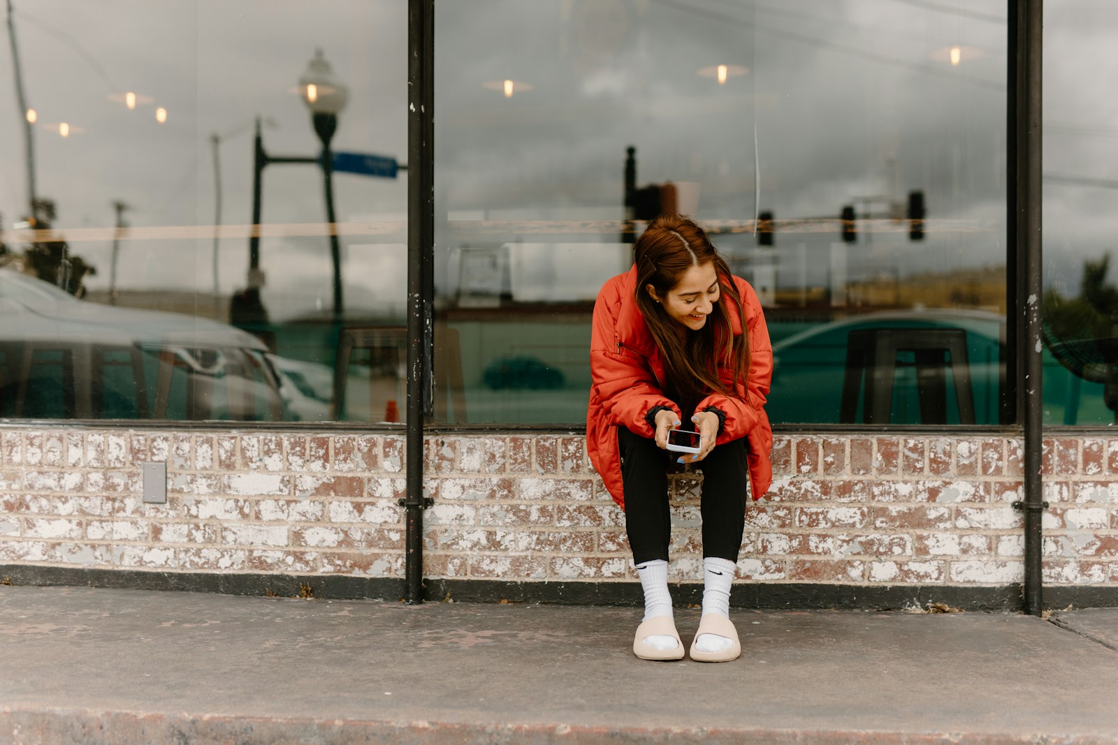 a woman sitting on a ledge in front of a building