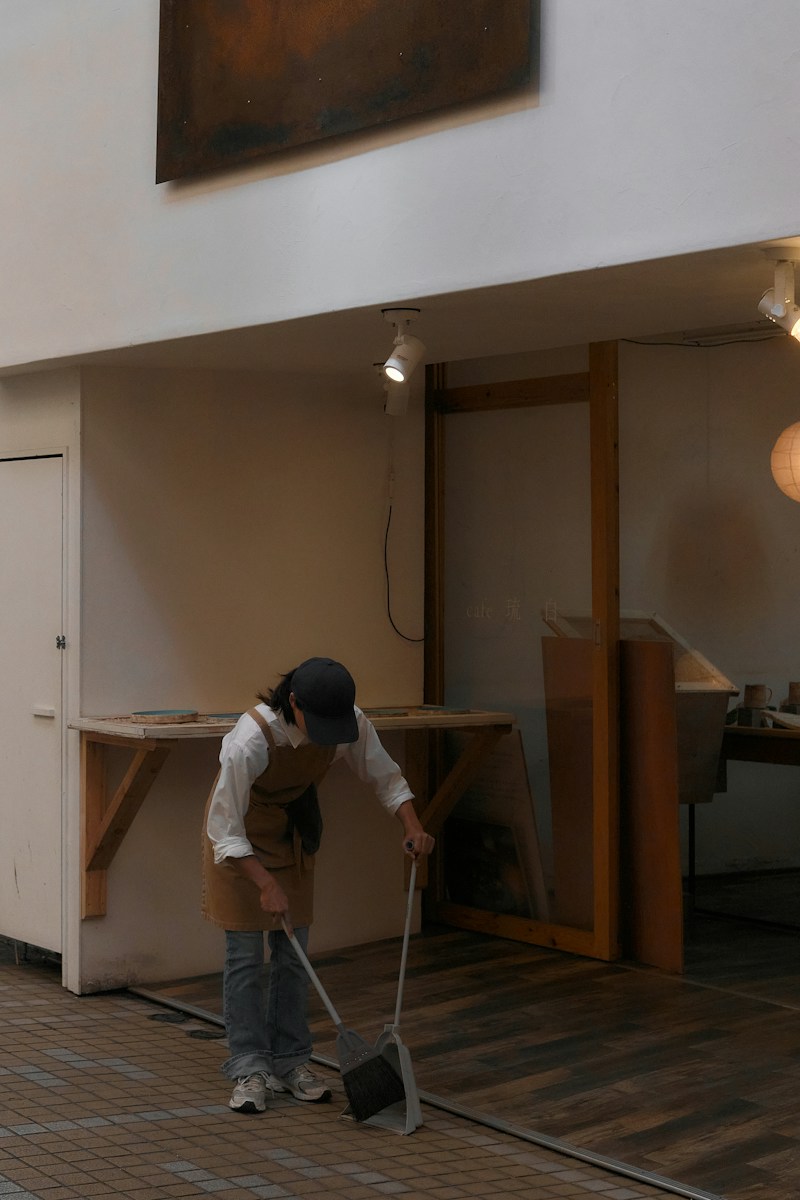 A person in a brown apron sweeping a floor in Naha, Okinawa