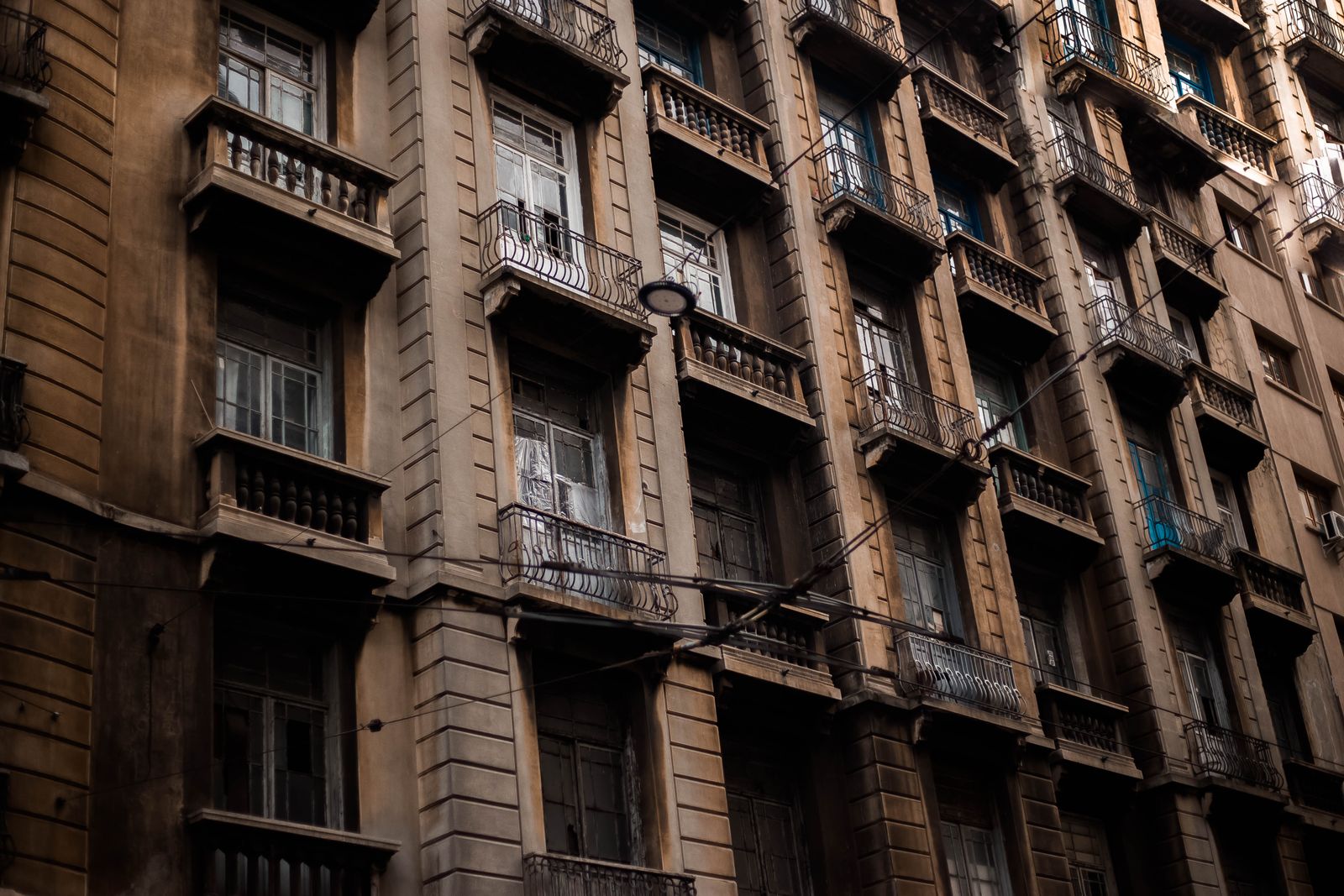 Low-angle view of an old residential building facade with multiple balconies, highlighting urban architecture.