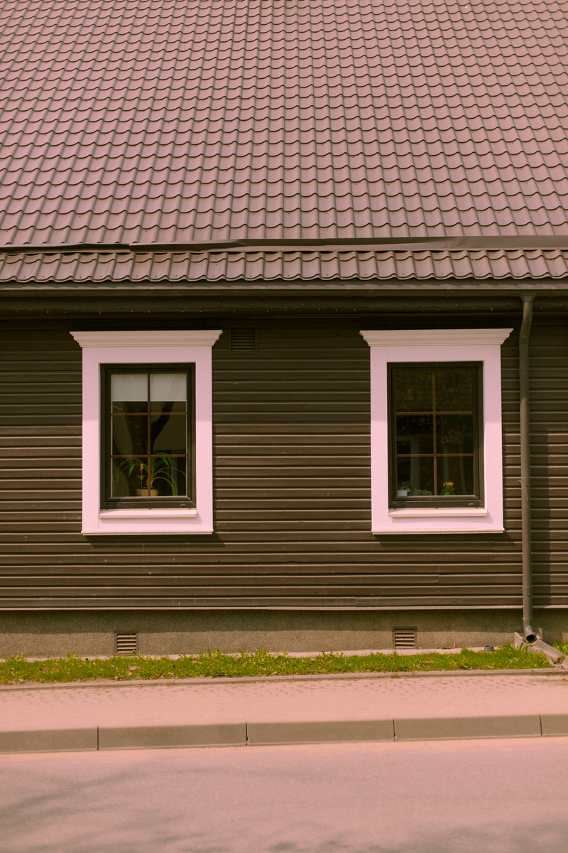 A cozy wooden house facade showcasing two windows and a tiled roof, ideal for architectural themes.