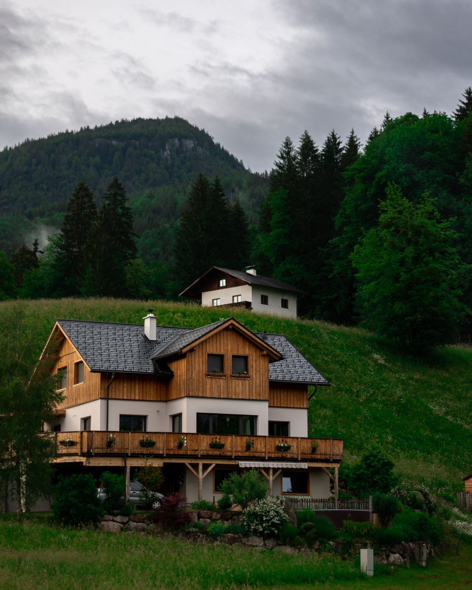A cozy house amidst lush greenery and mountains, perfect for a serene escape.