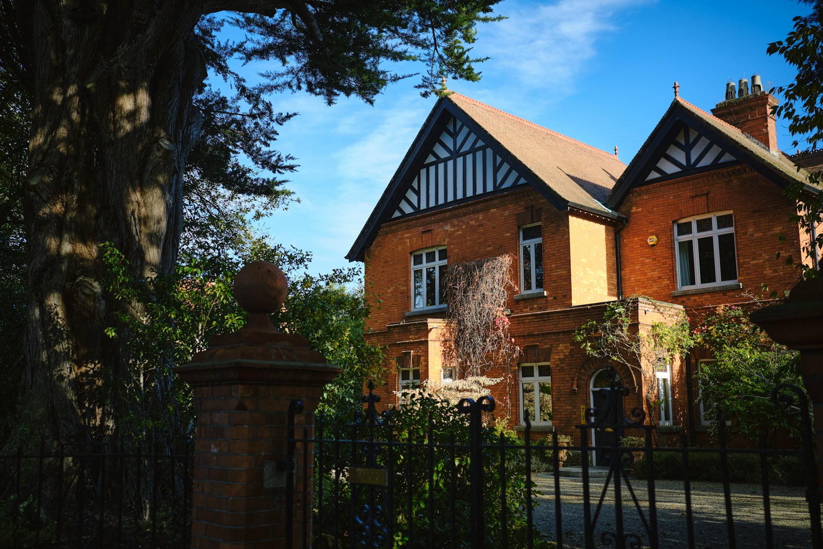 a large red brick house with a black iron fence