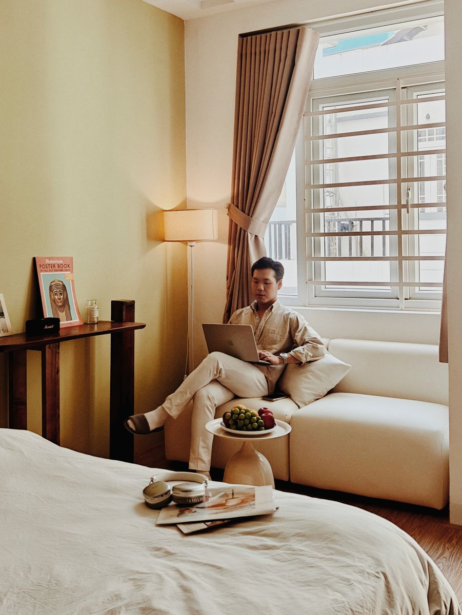 A cozy Airbnb room in Vietnam with a man relaxing and working on a laptop, creating a serene atmosphere.