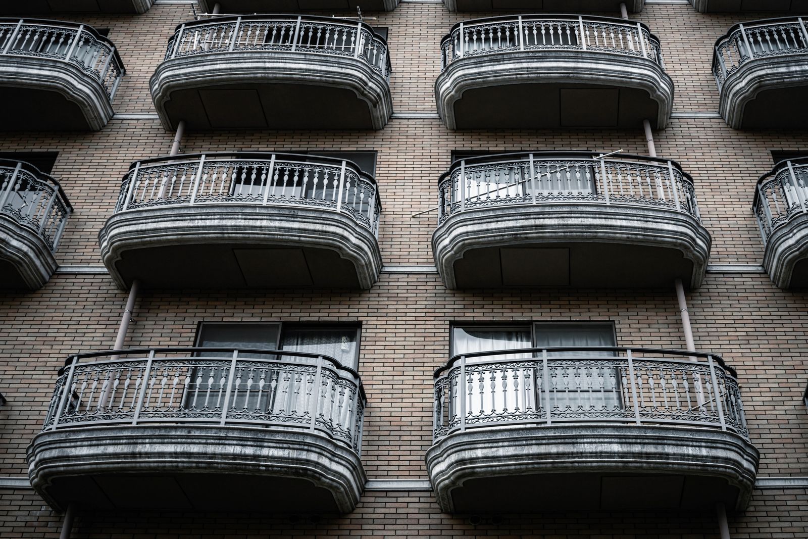Symmetrical view of ornate balconies on a brick apartment building facade.