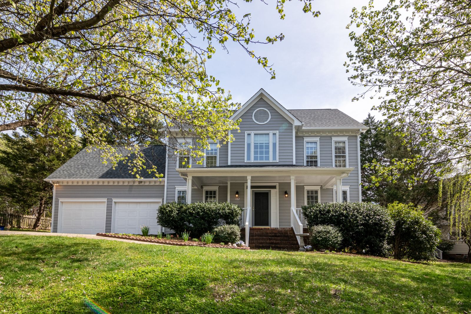 A beautiful suburban house surrounded by trees and lush greenery, perfect for families.