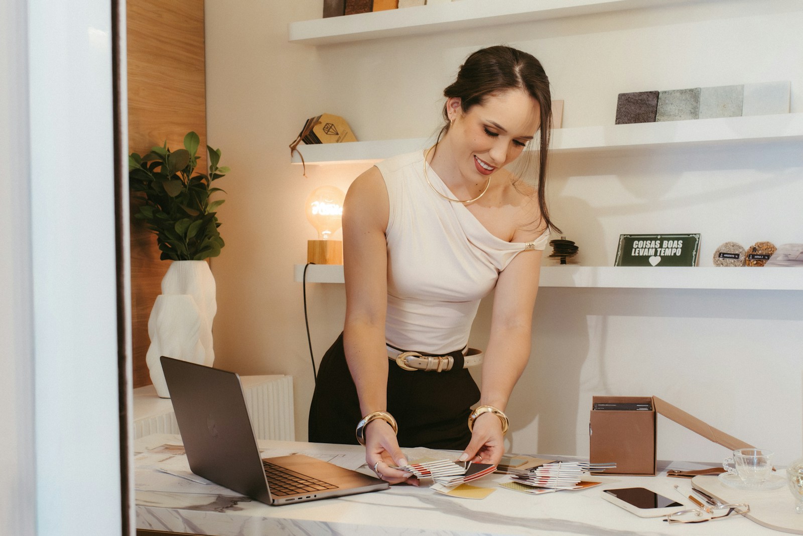 A smiling woman working at a desk with a laptop