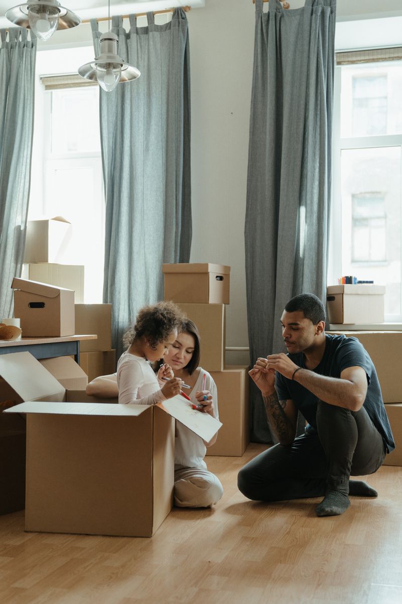A family enjoying the moving process while organizing cardboard boxes in their new home.