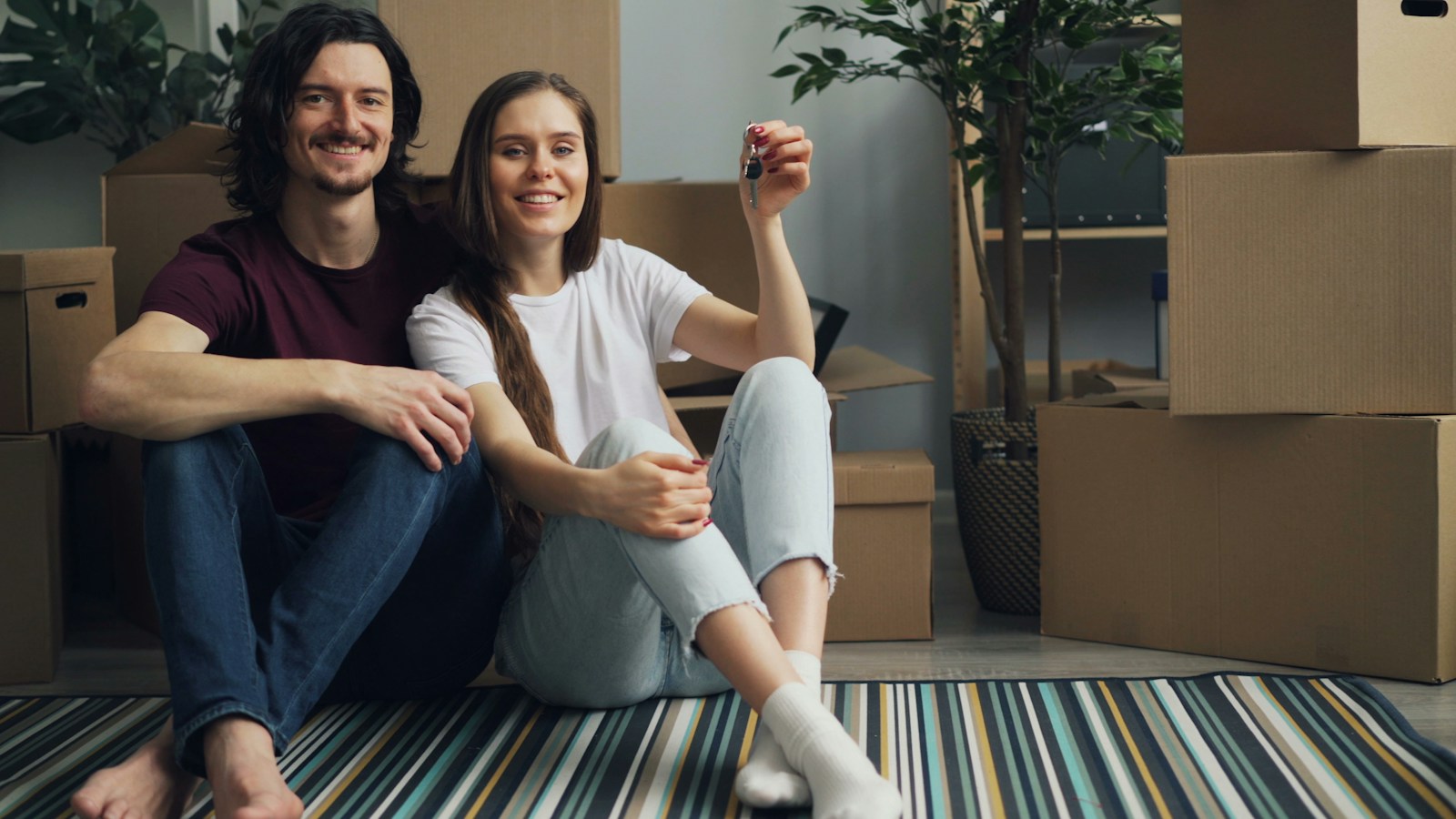 a man and a woman sitting on the floor in front of moving boxes