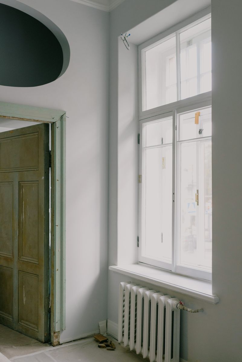 Interior of new flat with window and heating system near open door in daytime