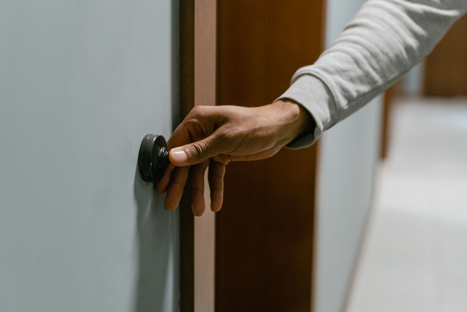Close-up of a hand pressing a doorbell in an indoor setting, illustrating alert routines.