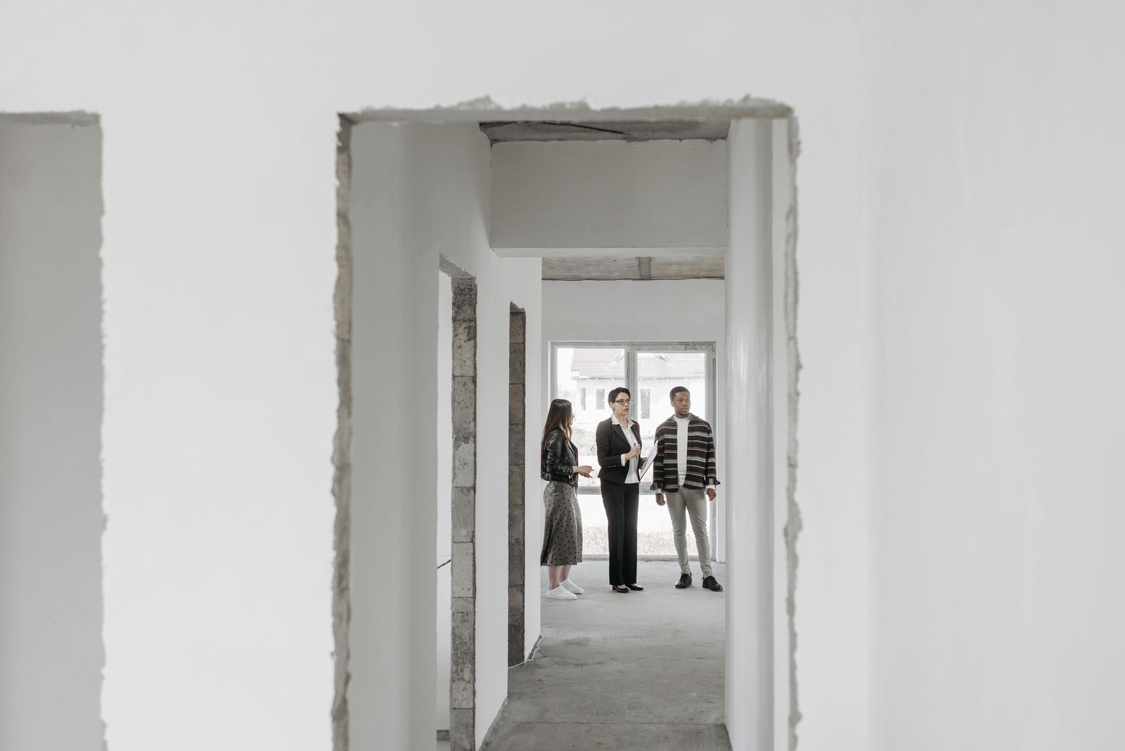 Real estate agent presenting a new house to potential buyers. Modern interior view.