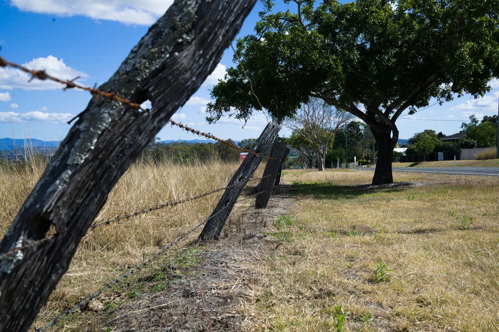 A barbed wire fence with a tree in the background