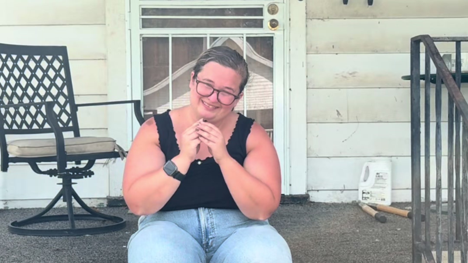 The homeowner sitting on the front steps of her white-sided Dayton, Ohio house, smiling with hands clasped, from the @annekane23 TikTok