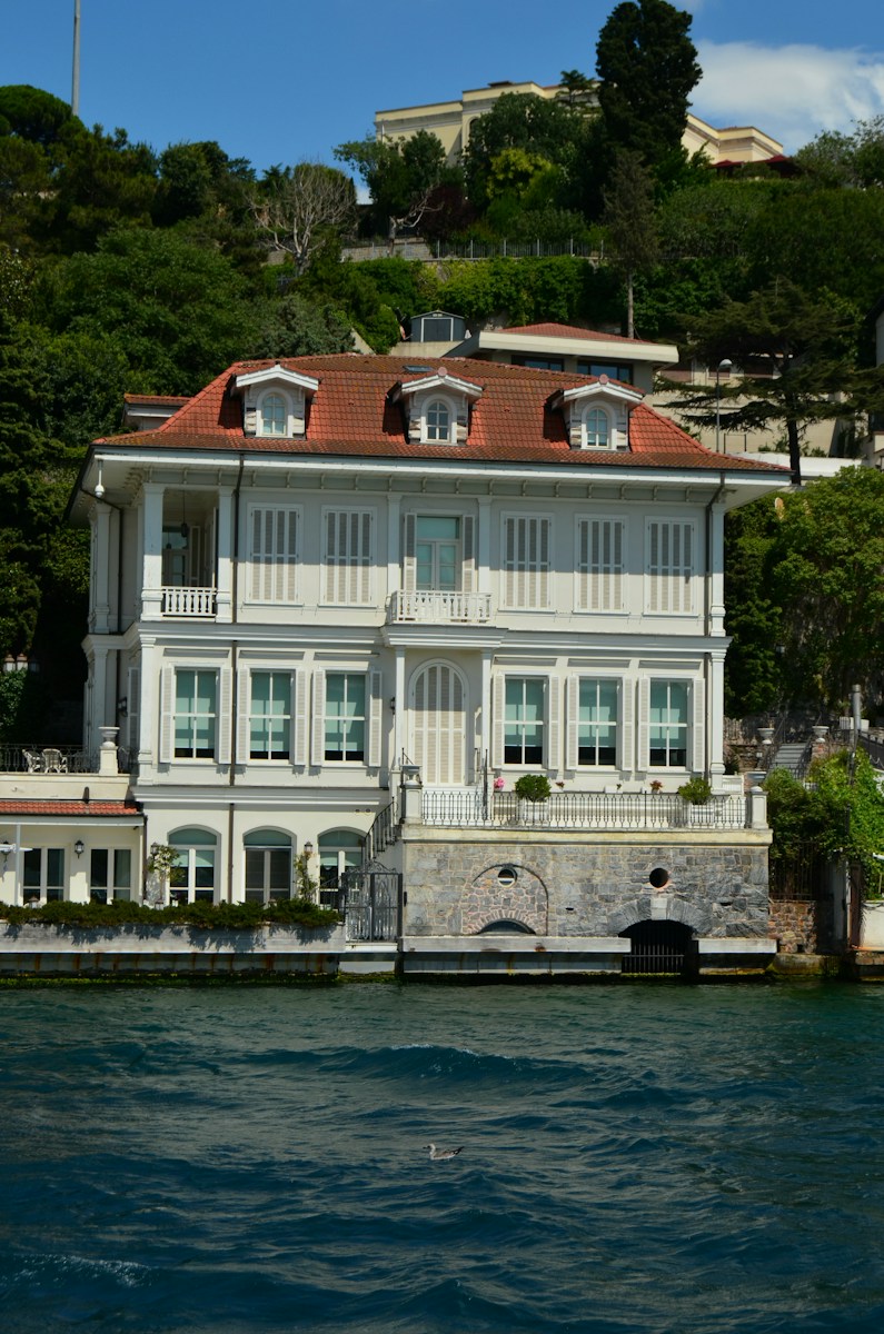 Grand white house with red roof on waterfront