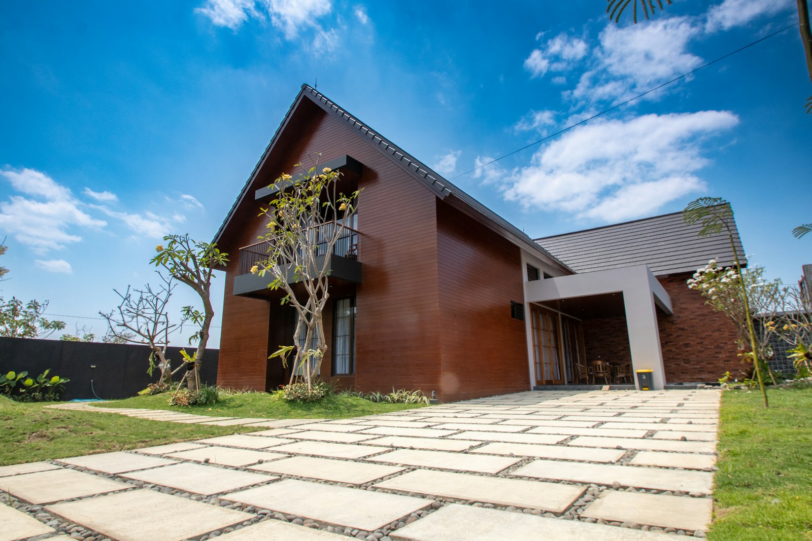 Modern wooden house with stone driveway and green lawn