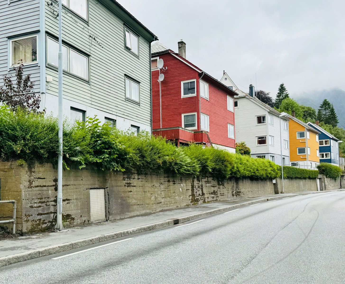 Colorful houses line a street with a stone wall