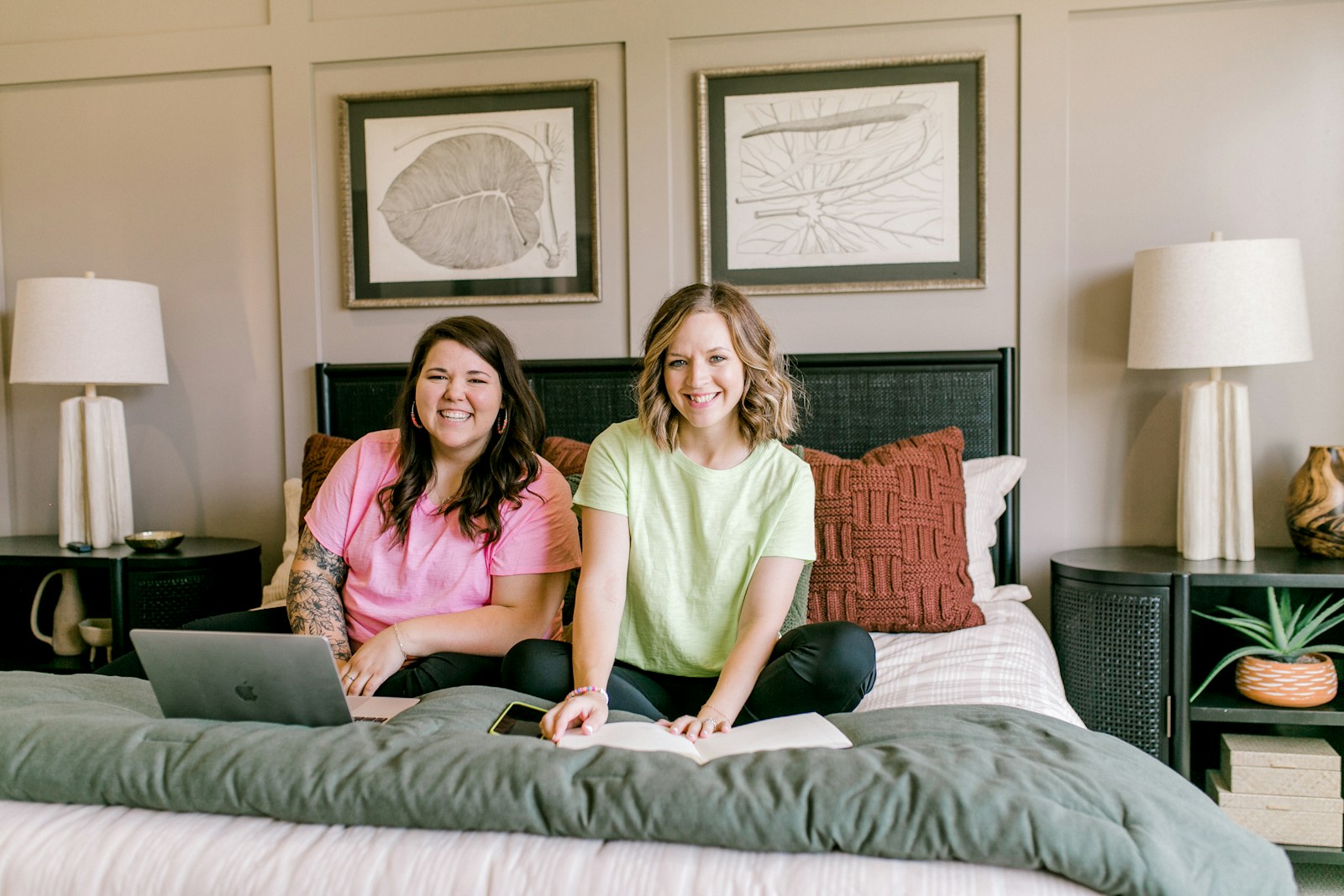 Two smiling women working on a bed