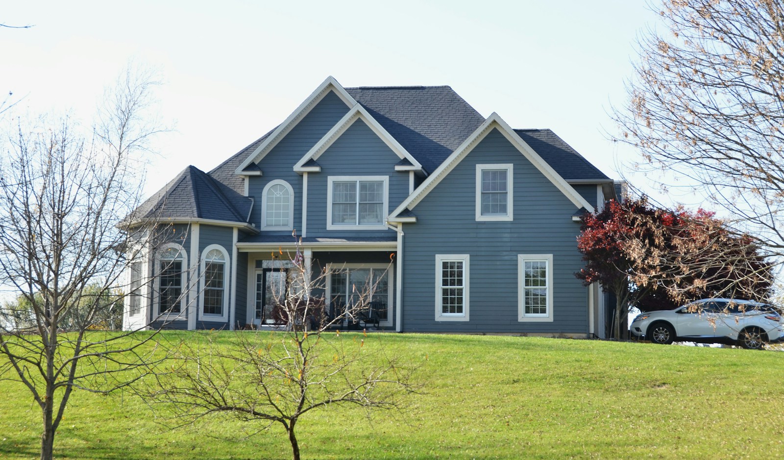A large blue house sits on a grassy hill