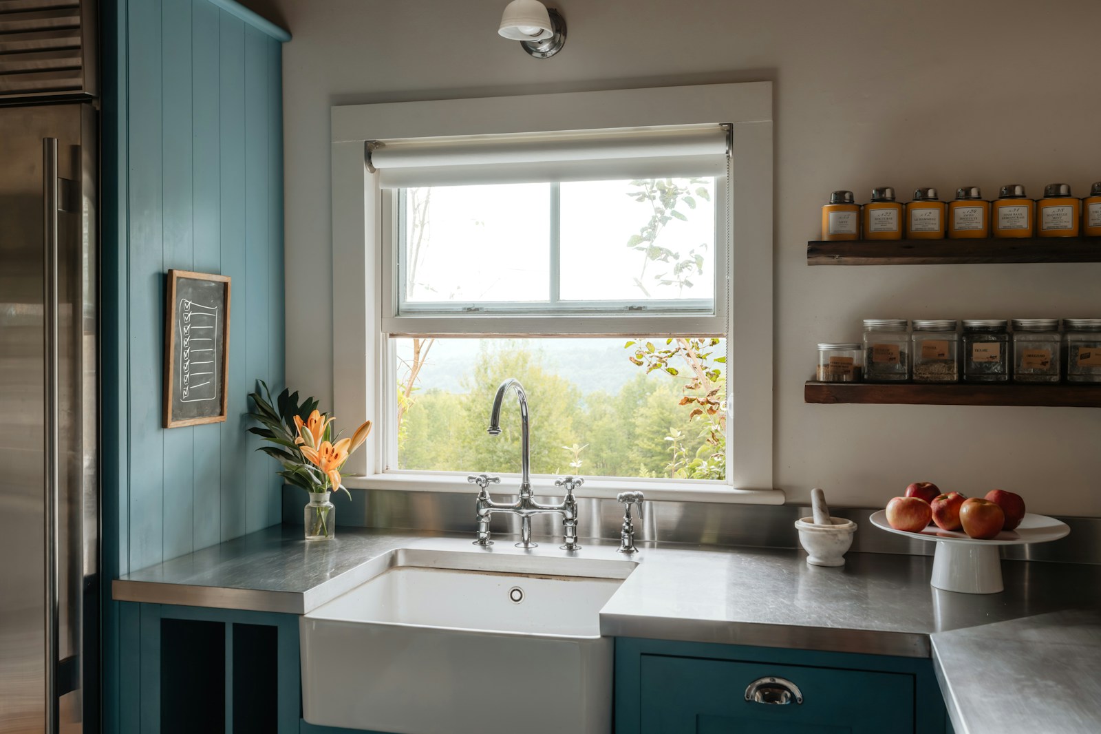 Farmhouse sink with stainless steel countertops and blue cabinets