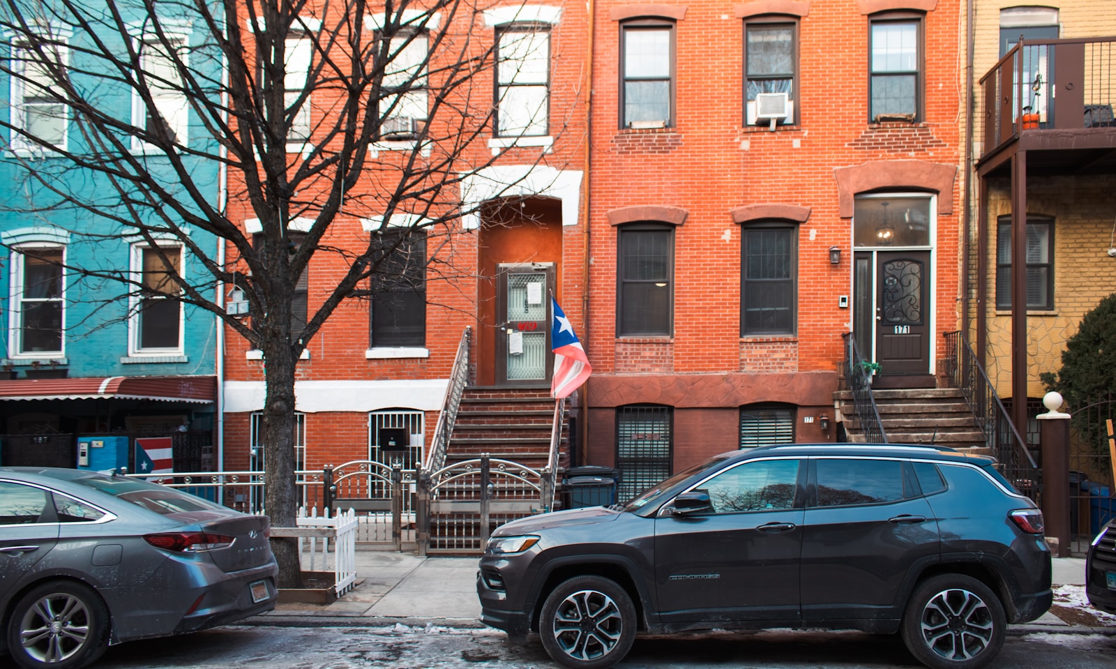Colorful townhouses line a street with parked cars