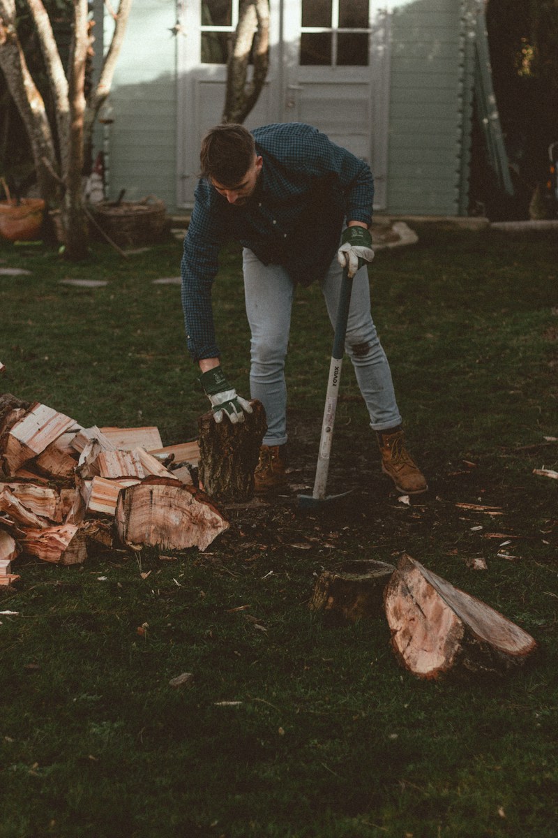 man in black jacket and blue denim jeans standing on brown wooden log during daytime